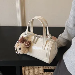 Stylish white patent leather Boston bag for women, featuring cute puppy pendant and dual handles.
