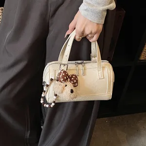 Detailed view of a trendy beige Boston handbag with cute puppy charm and dual zippers.