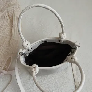 Detailansicht der cremeweißen Eimer Tasche mit Knotengriff und Schultergurt für Damenstil.