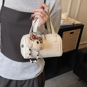 Chic patent leather boston handbag detail shot featuring a cute bear plush pendant, ideal.
