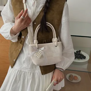 Detailansicht der schicken minimalistischen Eimertasche mit Perlenherz-Anhänger und Schleife.
