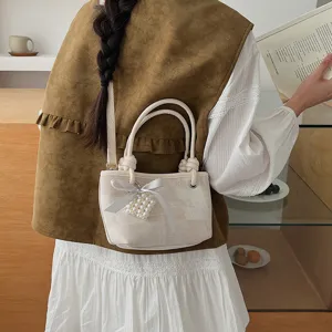 Detailansicht der trendigen Canvas Eimer Tasche mit Perlen Herz Anhänger und süßer Schleife.
