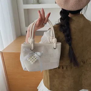 Detailansicht der minimalistischen Canvas-Eimerentasche mit eleganter Schleife und Perlenanhänger.