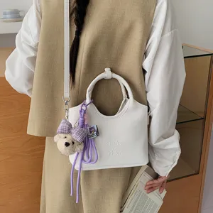 Weißer Leder Eimer-Tasche minimalistische Umhängetasche mit süßem Bärenanhänger Detail.