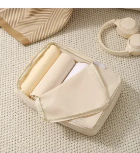 Gedetailleerd overzicht van beige reiskompressie-inpakblok met opgerolde kleding binnen.