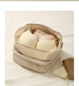 Gedetailleerd close-up van een beige meerlaagse ondergoedopbergtas met nette beha-organisatie.