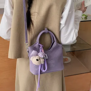 Detailansicht der stylischen violetten Beuteltasche mit süßem Bärenanhänger, elegante Umhängetasche.