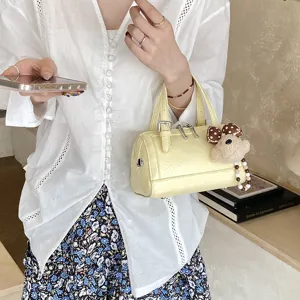 Yellow leather Boston handbag featuring a cute bear pendant and stylish design for daily use