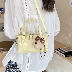 Yellow patent leather Boston handbag with a cute bear plush pendant for women daily use.