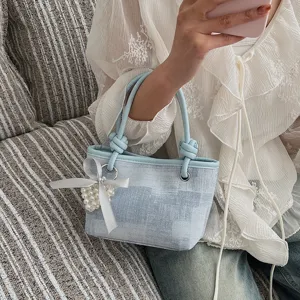 Detailansicht der stilvollen hellblauen Eimerhandtasche mit zauberhafter Perlen Schleife.