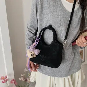 Detailansicht der stilvollen schwarzen Beuteltasche mit süßem Karo-Schleifen-Bär-Anhänger.