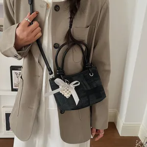 Nahaufnahme einer schicken schwarzen karierten Eimer Tasche mit Perlen Herz und Schleife.