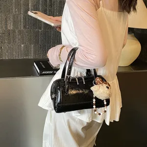 Black patent leather boston bag for women, trendy chic handbag with cute puppy plush charm pendant.