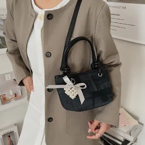 Nahaufnahme des stilvollen dunklen Jeans-Eimer-Beutels mit Perlenherz-Anhänger und schicker Schleife.