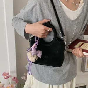 Schwarze Eimerhandtasche Detail mit süßem Plüschbären Anhänger und stilvollem geprägten Logo.