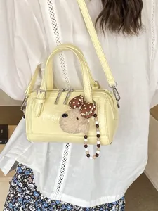 Chic yellow Boston pillow bag with cute plush dog charm, stylish crossbody handbag.
