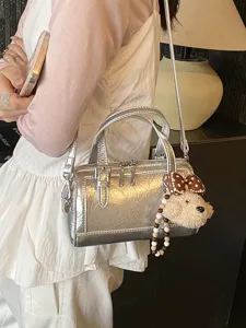 Trendy metallic silver boston shoulder bag for women, chic crossbody pillow bag with cute plush pendant.