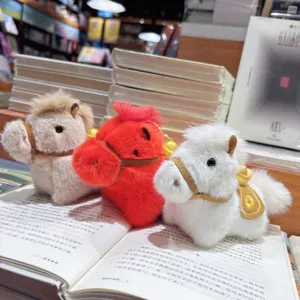 Nahaufnahme des Plüschpferdes, niedliches Sternzeichen Maskottchen mit Sattel und Goldbarren.