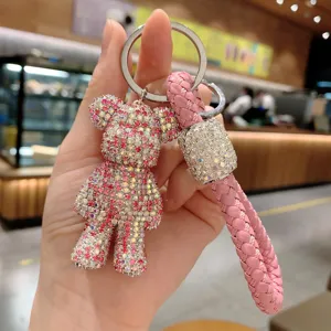 Grazioso portachiavi orsetto con strass, cinturino in pelle intrecciata rosa e anello in metallo.