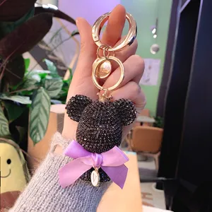 Rhinestone bear keychain detail view, featuring black crystal head, purple bow and gold ring.