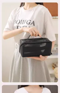 Detail view of black mesh makeup bag held by model, portable travel storage organizer.