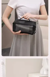 Black mesh cosmetic bag detail view, portable toiletry storage pouch with zipper and handle.
