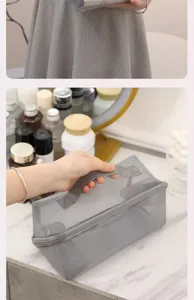 Gray mesh cosmetic bag with handle, large capacity travel makeup storage organizer detail.