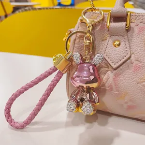 Portachiavi con coniglietto in strass metallico e cinturino intrecciato per borsa da donna.