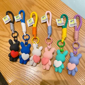 Cute resin rabbit keychain with heart pendant, colorful woven rope bag charm and car key accessory.