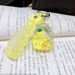 Close-up of cute liquid quicksand acrylic keychain with pineapple and fruit inside for bags.
