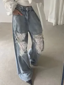Femme jean bleu large avec des patchs en dentelle déchirée, pantalon élégant décontracté.