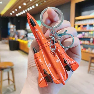 Close-up detail shot of a creative alloy mini fighter jet keychain in vibrant orange finish.