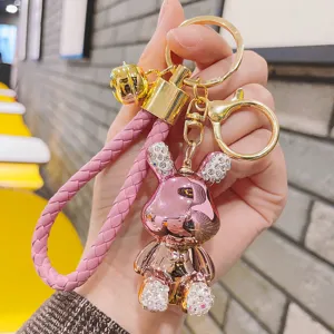 Dettaglio portachiavi coniglio rosa metallizzato, orecchie in strass e cinturino intrecciato
