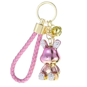 Portachiavi con coniglio in metallo di lusso con cinturino in pelle intrecciata rosa e campanello.