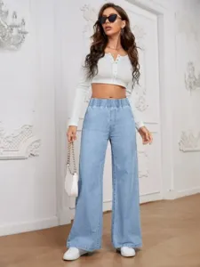 Detailed view of casual high-waisted wide leg light blue denim jeans styled with a top.