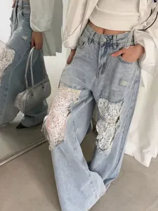 Jeans amples bleu clair tendance avec empiècements en dentelle blanche pour un look quotidien.