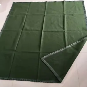Detail view of the dark green camping blanket showing its folded texture and stitched edge.