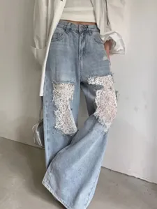 Détail de jean large bleu clair pour femme, genoux déchirés avec empiècement en dentelle blanche.