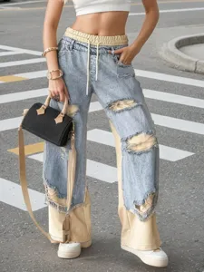 Detail view of women's casual straight leg jeans with drawstring and distressed patchwork.