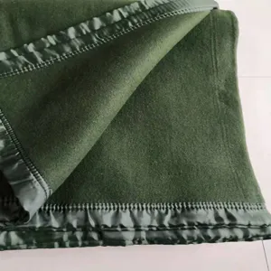 Detailed view of dark green wool blanket, thick fabric texture with matching satin border.