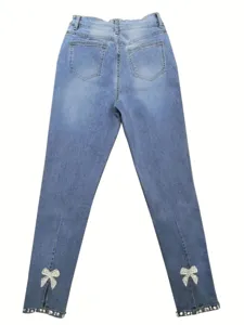 Details of womens light blue slim fit denim jeans featuring rhinestone bow split ankles and back pockets.