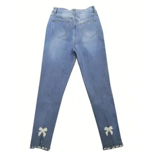 Washed stretch slim fit women's denim jeans with rhinestone bow split hem details.