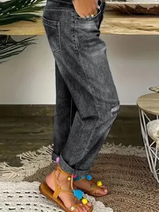 Détail de jean déchiré décontracté pour femme à taille haute avec revers élégants.