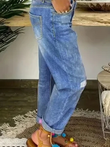 Jean femme bleu clair déchiré taille haute avec détails de pompons colorés revers.