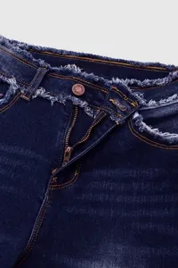 Primo piano di jeans da donna blu scuro con cintura sfilacciata e bottone in metallo.