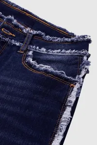 Primo piano dettagliato di jeans da donna blu scuro con frange eleganti sui bordi grezzi.
