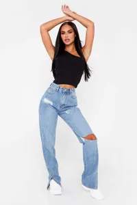 Close-up detail of light blue ripped straight jeans with split hem design and raw edge.