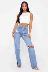 Close-up details of women casual distressed straight-leg denim jeans with stylish hem slit.
