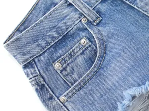 Blue denim shorts pocket and rivet detail closeup shot featuring contrast stitching.