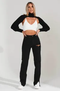 Detailed view of women street style black straight leg ripped jeans with white top and shrug.
